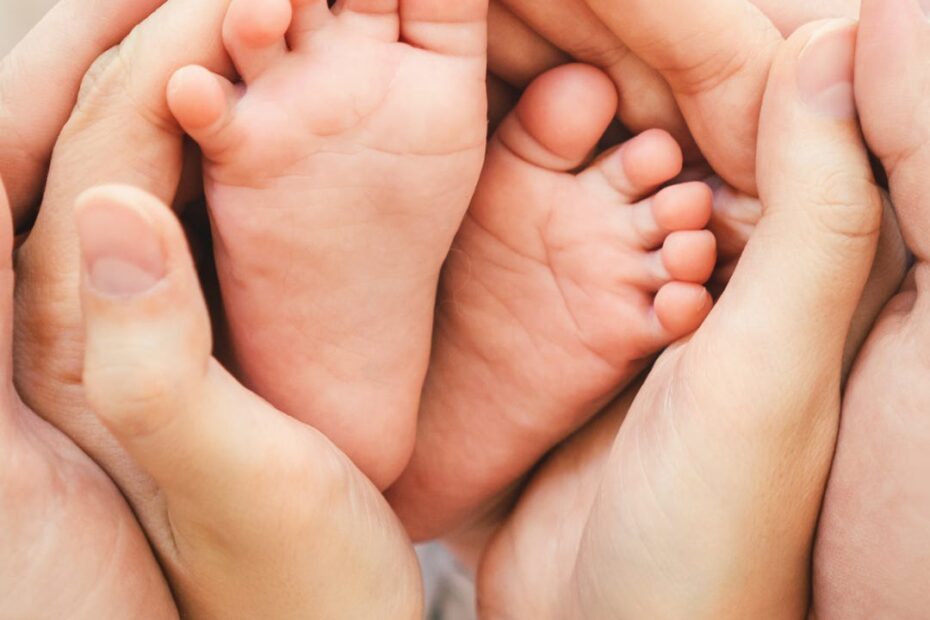 baby feet surrounded by mother and father's hands